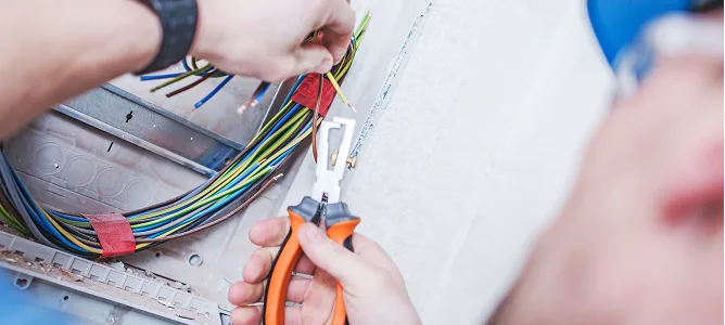 Elektriker isoliert mit Zange Kabel an einer Unterputzdose ab