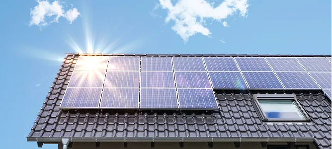 Photovoltaikmodule auf einem dunklen Ziegeldach bei Sonnenschein
