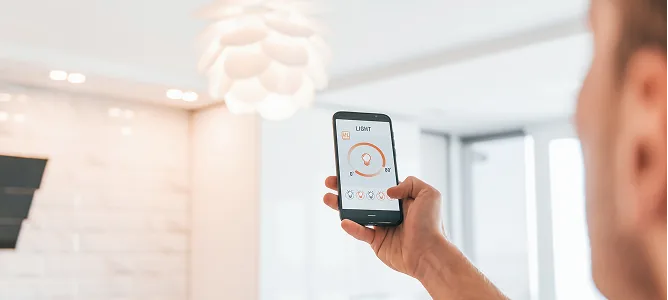 Mann steuert die Raumbeleuchtung per Smartphone-App