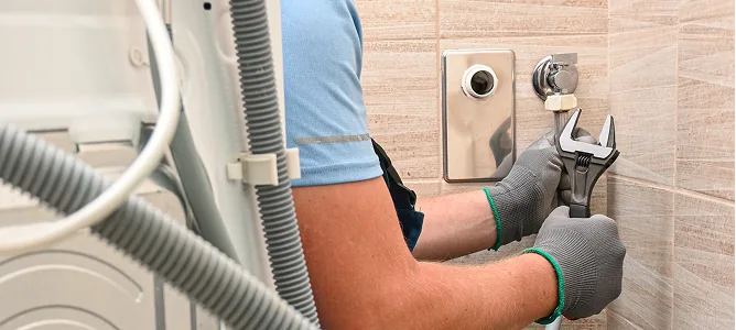 Handwerker schließt ein Haushaltsgerät an der Wand an