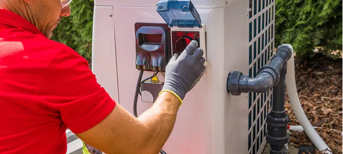 Techniker prüft den elektrischen Anschluss einer Wärmepumpe im Garten