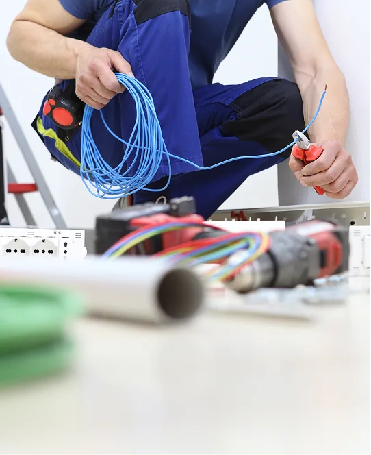 Elektriker mit Kabelrolle und Abisolierzange an der Werkbank