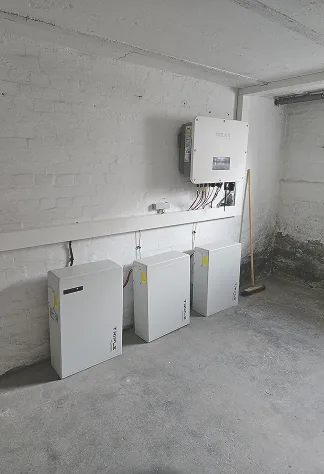 Wechselrichter und Batteriespeicher im Kellerraum an einer Ziegelwand