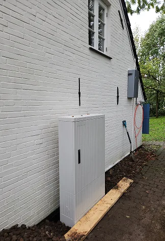 Neue Zähleranschlusssäule an der Außenwand eines weißen Hauses