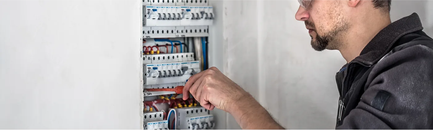 Elektriker arbeitet an Sicherungsautomaten in einem offenen Verteilerkasten