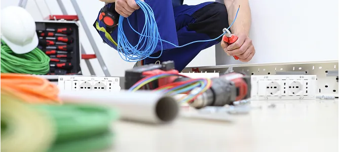 Elektriker bereitet Kabel und Steckdosen auf einer Werkbank vor